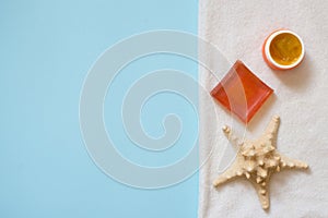 Orange soap and sea star on white towel on blue background with copy space. spa bath concept