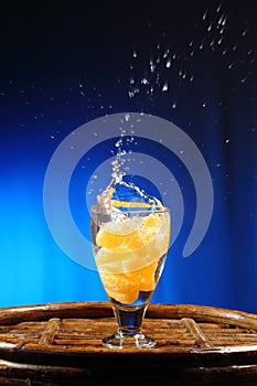 Orange splashing into glass of water