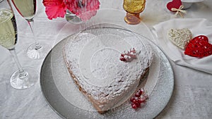 Orange sponge cake heart shaped on plate, sprinkle with powdered sugar. Champagne, Valentines day