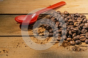 Orange spoon, coffee grounds and beans on wooden board