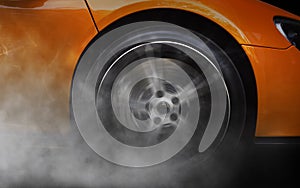 Orange Sport Car with detail on spinning and smoking wheels/tires doing burnouts