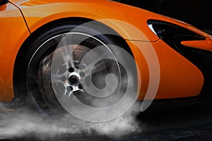 Orange Sport Car with detail on spinning and smoking wheels/tires doing burnouts