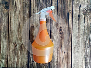 Orange spray bottle on wooden table background