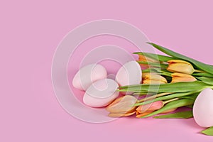 Orange spring flower tulips with Easter eggs on pink background