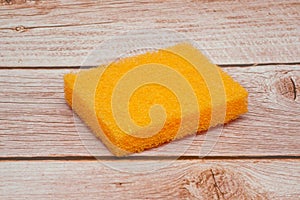 Orange square foam scouring sponge with wood background