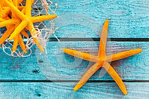 Orange starfish on turquoise boards with fish net