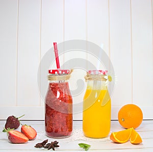 Orange and strawberry juice in a glass jar, on a white background.