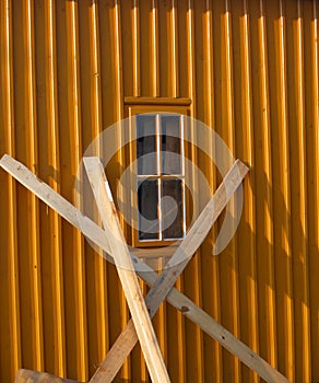 Orange structured wall with window and leant planks