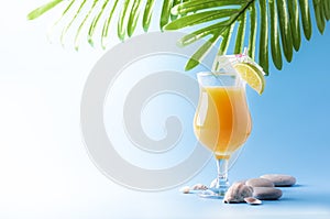 Orange summer alcoholic cocktail with mango juice, rum, liqueur, lime and ice, blue background, copy space