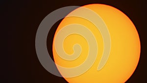 Orange sun ball close up moving frame in black background.