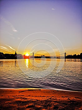 Orange Sundown over the sandy Beach of the river Rhein in Cologne with sky, Chappell and bridge landscape