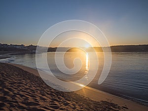 Orange sunrise at empty sand beach Praia da Franquia at Vila Nova de Milfontes with Mira river and fort Forte de photo