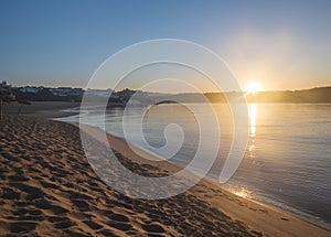 Orange sunrise at empty sand beach Praia da Franquia at Vila Nova de Milfontes with Mira river and fort Forte de photo