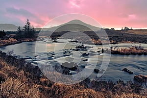 Orange sunrise landscape scenery with river and mountains under dramatic skies at Derryclare, connemara, galway, Ireland