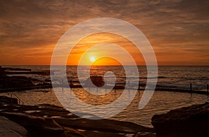 Orange sunrise over rock pool at Maroubra, Sydney Australia