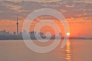 Orange sunrise reflected in Toronto bay with city skyline