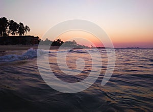 Orange sunset on the beach inside the sea with waves