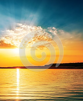 Orange sunset in clouds over river