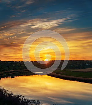 Orange sunset in clouds over river