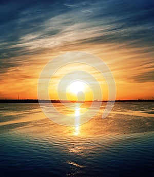 orange sunset in dramatic clouds over river