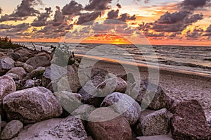 Orange sunset landscape of Baltyk sea with rocks, waves and clouds