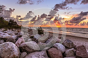 Orange sunset landscape of Baltyk sea with rocks, waves and clouds