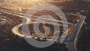 Orange sunset over highway road junction overpass. Roundabout car traffic aerial background