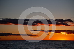 Orange sunset over horizon of lake water at dusk in the evening