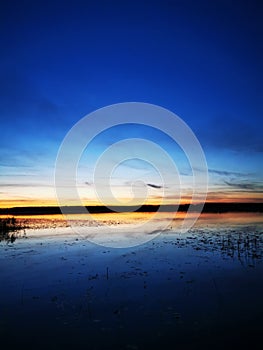 Orange sunset over lake with blue sky