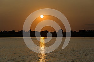 Orange sunset over trees and a lake