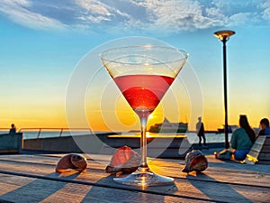 Orange Sunset at pier people relaxing on promenad and glass of juice on wooden table in Tallinn Baltic Sea  travel to Estonia