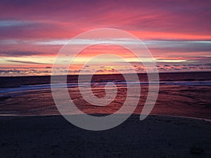 Orange sunset sky with beach, ocean and clouds