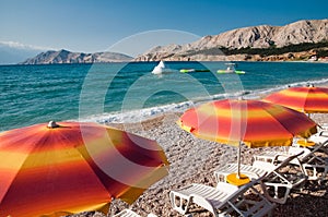 Orange sunshades and deck chairs on Baska beach - Krk Croatia