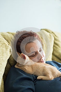 Orange tabby kitten sleeping in the lap of a woman