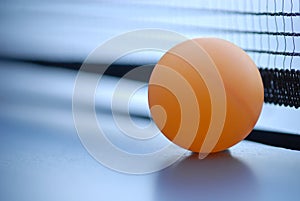 Orange table tennis ball on blue table with net