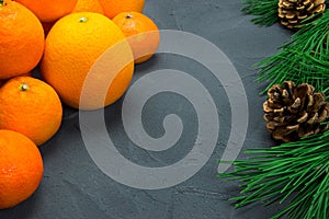 Orange and tangerine with branch christmas tree cone on black concrete background