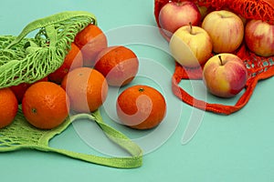 Orange tangerines and apples lie in an ecological reusable mesh bags