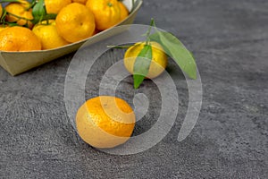 orange tangerines with green leaves in a cardboard tray on a table