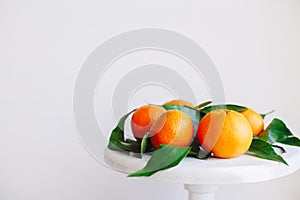 Orange tangerines on grey background in New Year`s decor with brown pine cones and green leaves. Christmas decoration with