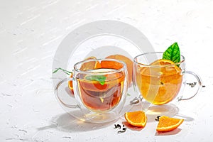 Orange tea in glass cups with ripe fruits. Refreshment seasonal drink, conceptual background