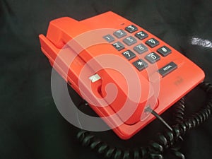 orange telephone on a black background, close-up of the phone