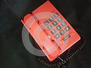 orange telephone on a black background, close-up of the phone