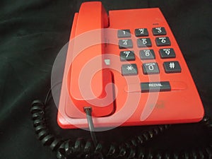 orange telephone on a black background, close-up of the phone