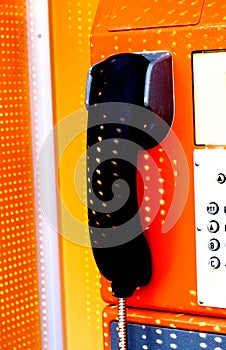 Orange telephone receiver with shawdow light.