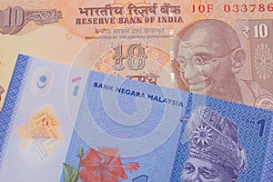 A orange ten rupee bill from India paired with a blue, plastic one ringgit bank note from Malaysia.