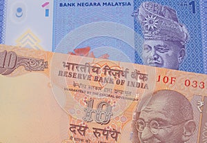 A orange ten rupee bill from India paired with a blue, plastic one ringgit bank note from Malaysia.