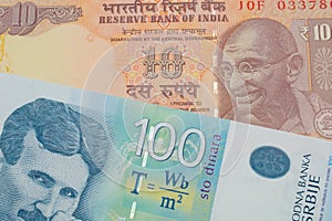 A orange ten rupee bill from India paired with a bue and white one hundred Serbian dinar note.