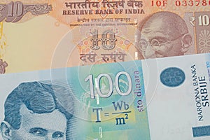 A orange ten rupee bill from India paired with a bue and white one hundred Serbian dinar note.