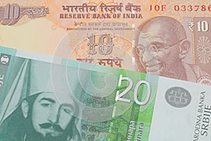 A orange ten rupee bill from India paired with a green and white twenty dinar banknote from Serbia.