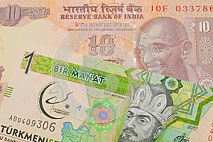 A orange ten rupee bill from India paired with a green and yellow one manat note from Turkmenistan.